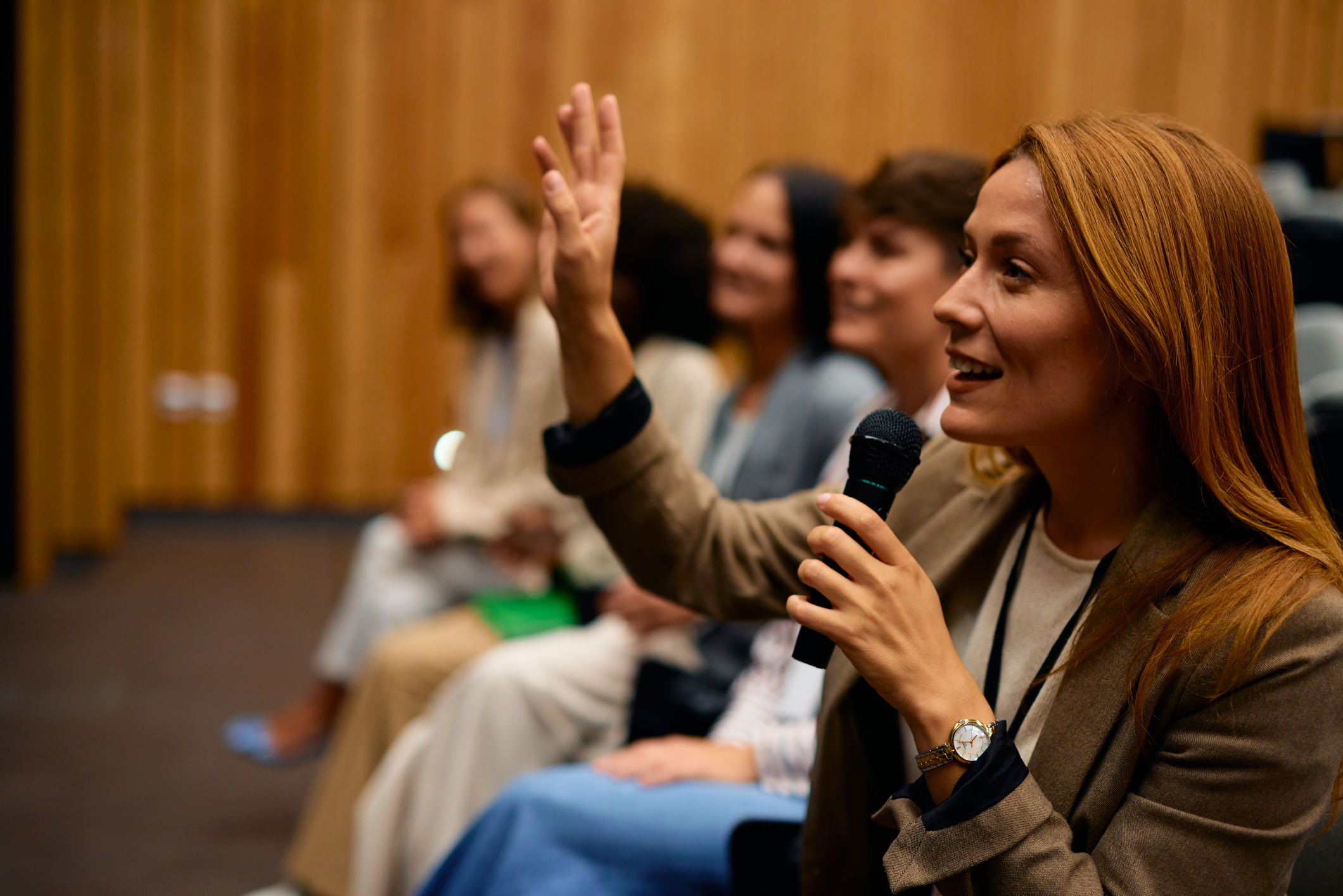 Business woman raising hands to ask speaker questions at a conference