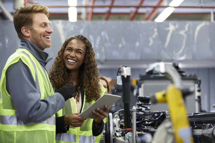 two workers in a manufacturing plant smiling