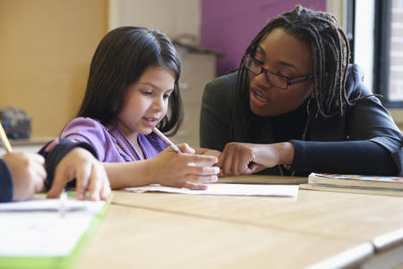 Teacher helping young girl with assignment