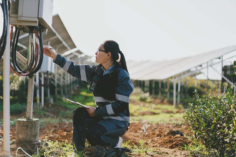 Photo of a female technician working on a solar farm.