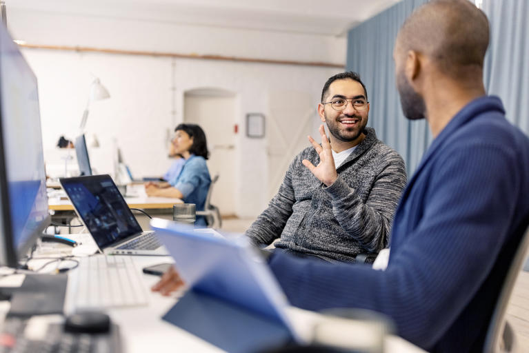 Computer programmers discussing code that they working on while working at office