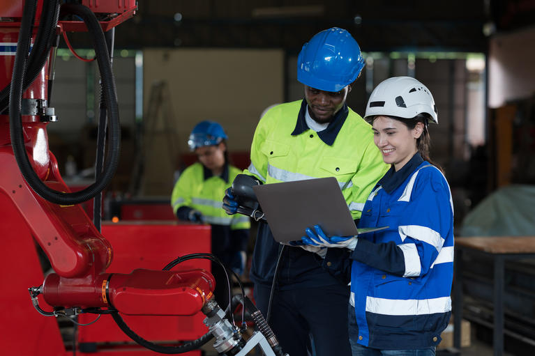 Male and female technician working with robot arm system welding.