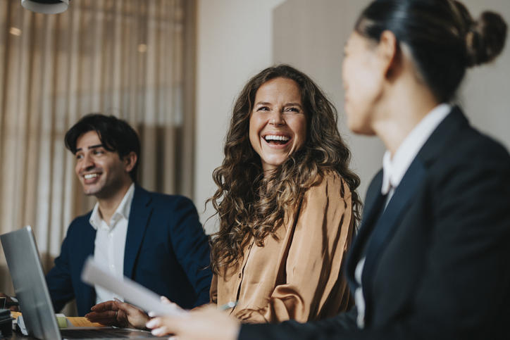woman smiling at another woman nam behind her at a conference table