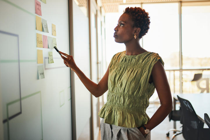 dark skinned black woman with afro analyzes post it notes 
