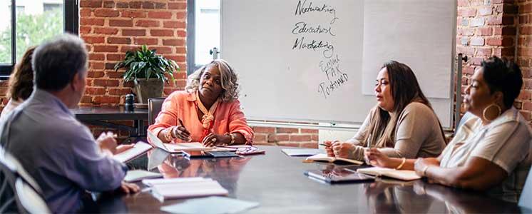Female professional leading a meeting in a conference room with other professionals.