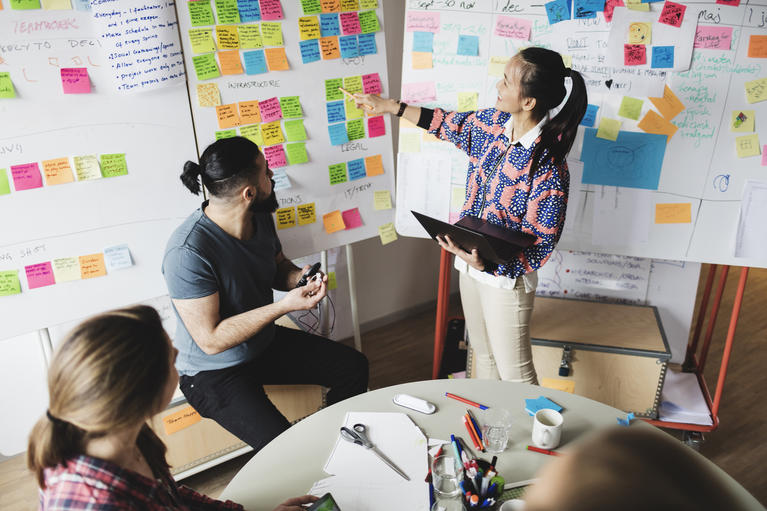  businesswoman showing notes and explaining colleagues during meeting