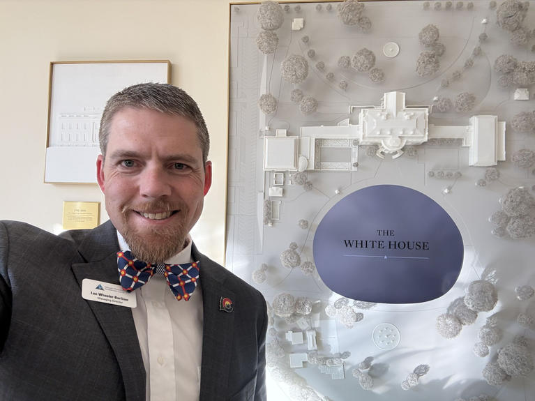 Lee Wheeler-Berliner poses in front of a sign that reads "White House"