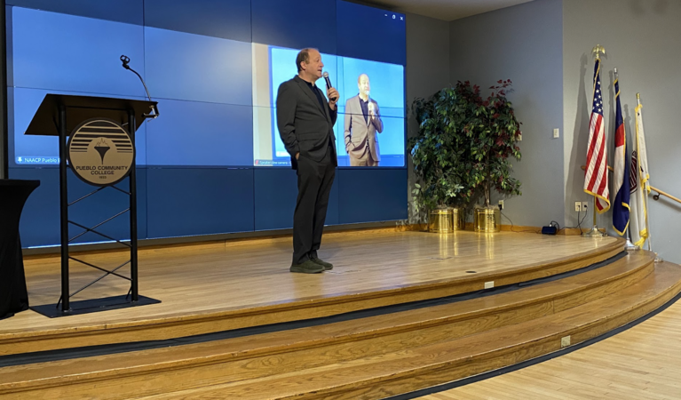 Governor Jared Polis at CWDC Meeting with microphone on stage
